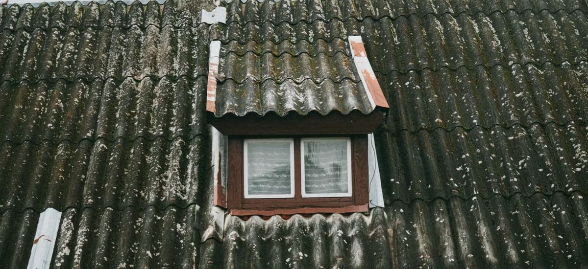 Detailed view of a moss-covered roof with a small window in rural Poland, capturing rustic charm.
